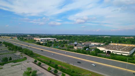 Modern-drone-rises-above-empty-parking-lot-and-highway-with-landscape-in-the-background