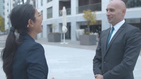 business colleagues meeting outside, shaking hands, smiling and talking together