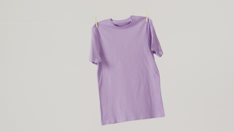 Video-of-close-up-of-purple-t-shirt-hanging-on-white-background