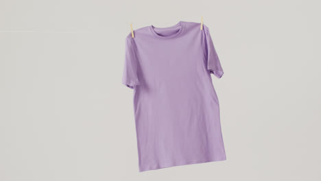 video of close up of purple t shirt hanging on white background