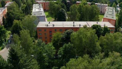 Aerial-drone-shot-of-flat-apartment-complex-in-the-middle-of-city-during-summer