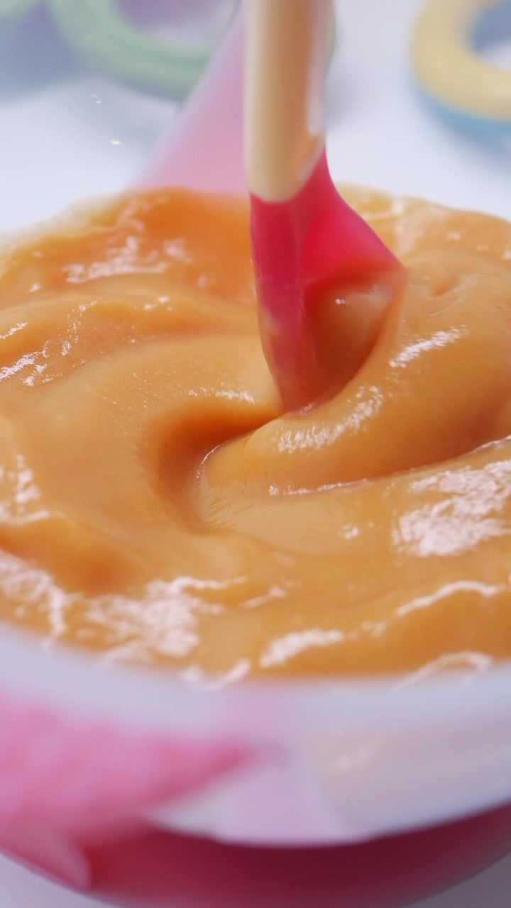 Silikonspatel som blander tykk oransje puré i en bolle