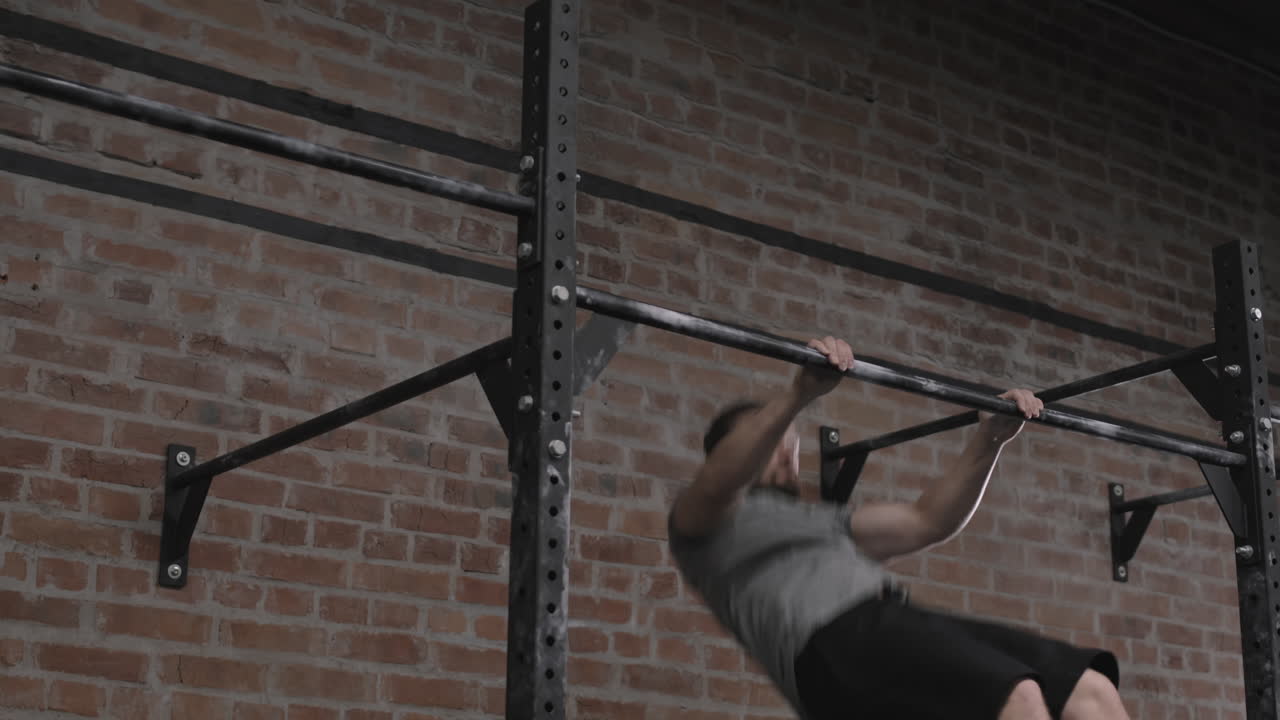 Young Sporty Man Exercising on Horizontal Bar in Gym