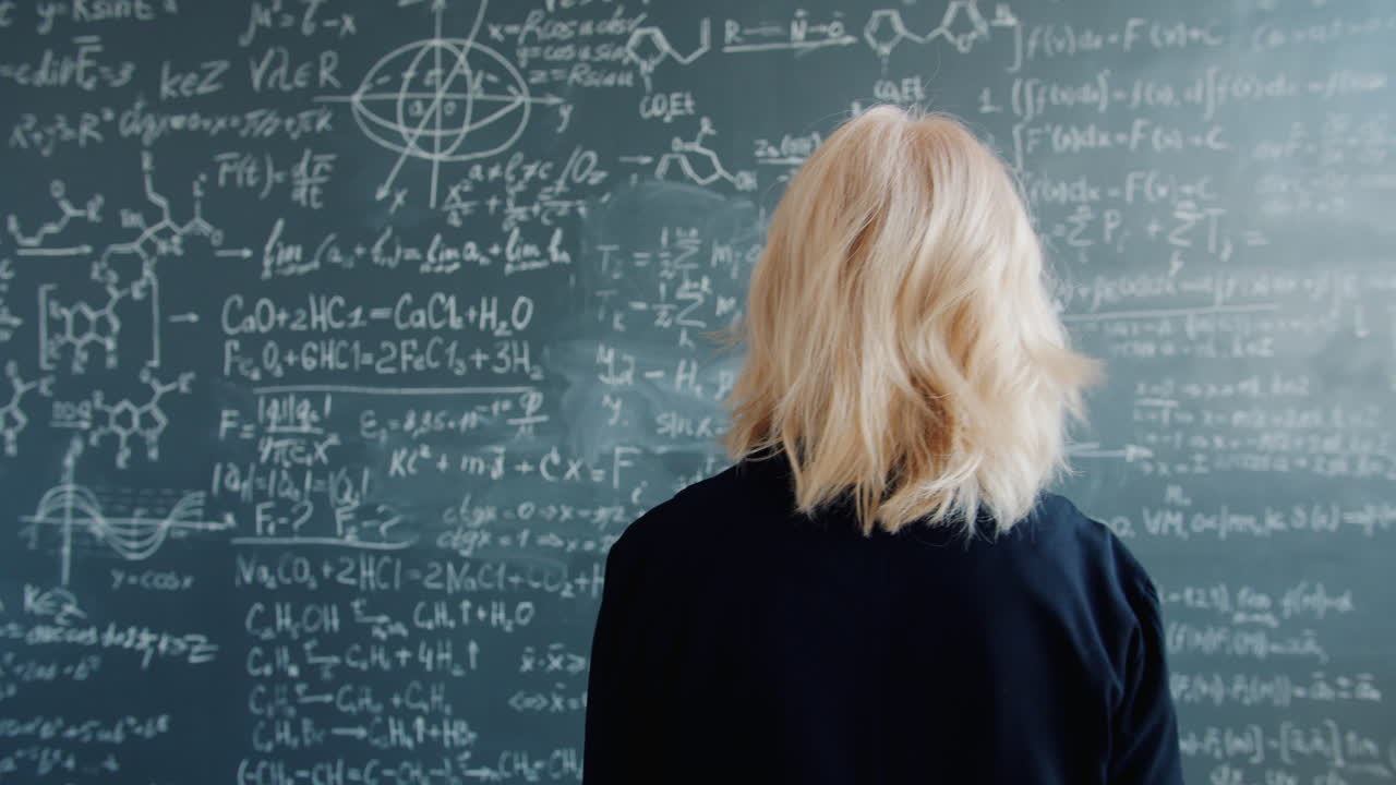 Woman looking at a chalkboard full of equations