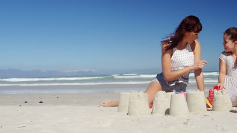 Mother-and-daughter-making-sand-castle-at-beach