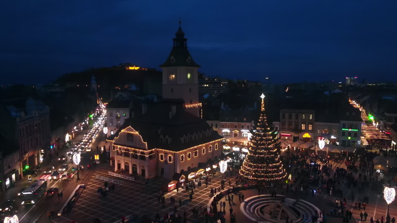 Aerial drone view of The Council Square in Brasov at night, Romania. Old city centre decorated for Christmas. County Museum of History, buildings, people