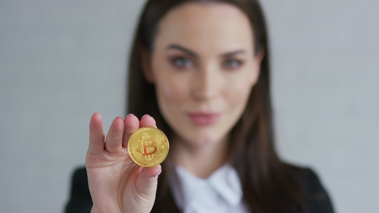 mujer joven y guapa con chaqueta negra demostrando bitcoin y mirando a la cámara