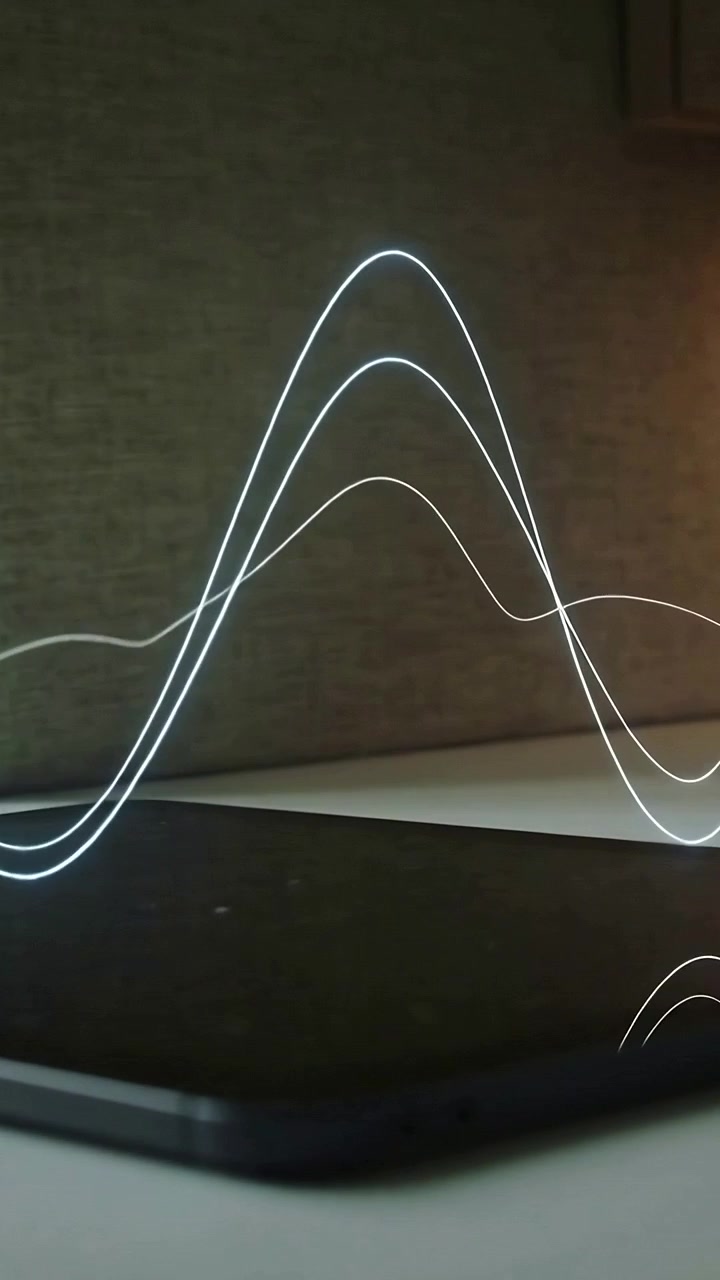 Vertical video: Bright point starting left drawing waves over keyboard, tablet creating glass glow