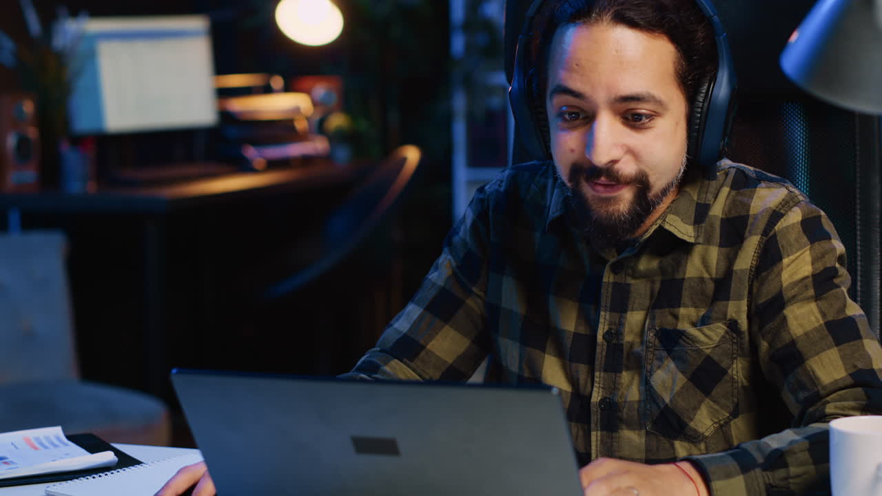 Happy man drinking coffee and writing emails at home office desk