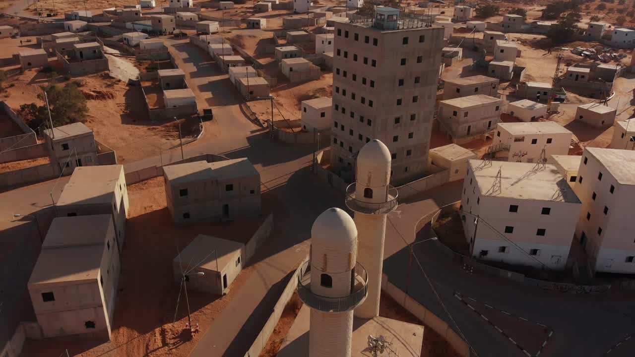 aerial shot of two mosques and a big building in an old empty city in the desert in palestine near Gaza at sunset.