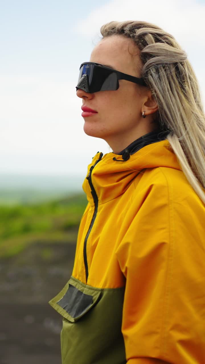 Young Woman in Yellow Jacket and Sunglasses Looking at Landscape