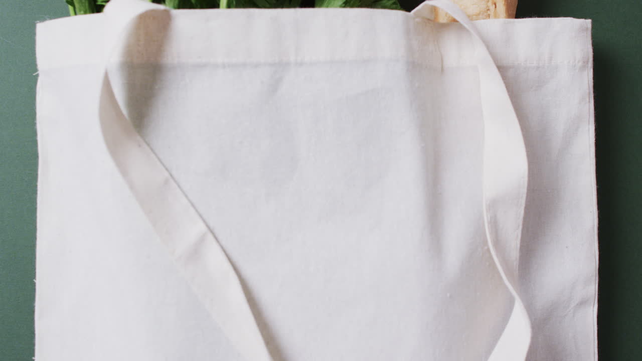 video de una bolsa de lona blanca con perejil, col rizada y baguette, copia espacio en fondo verde
