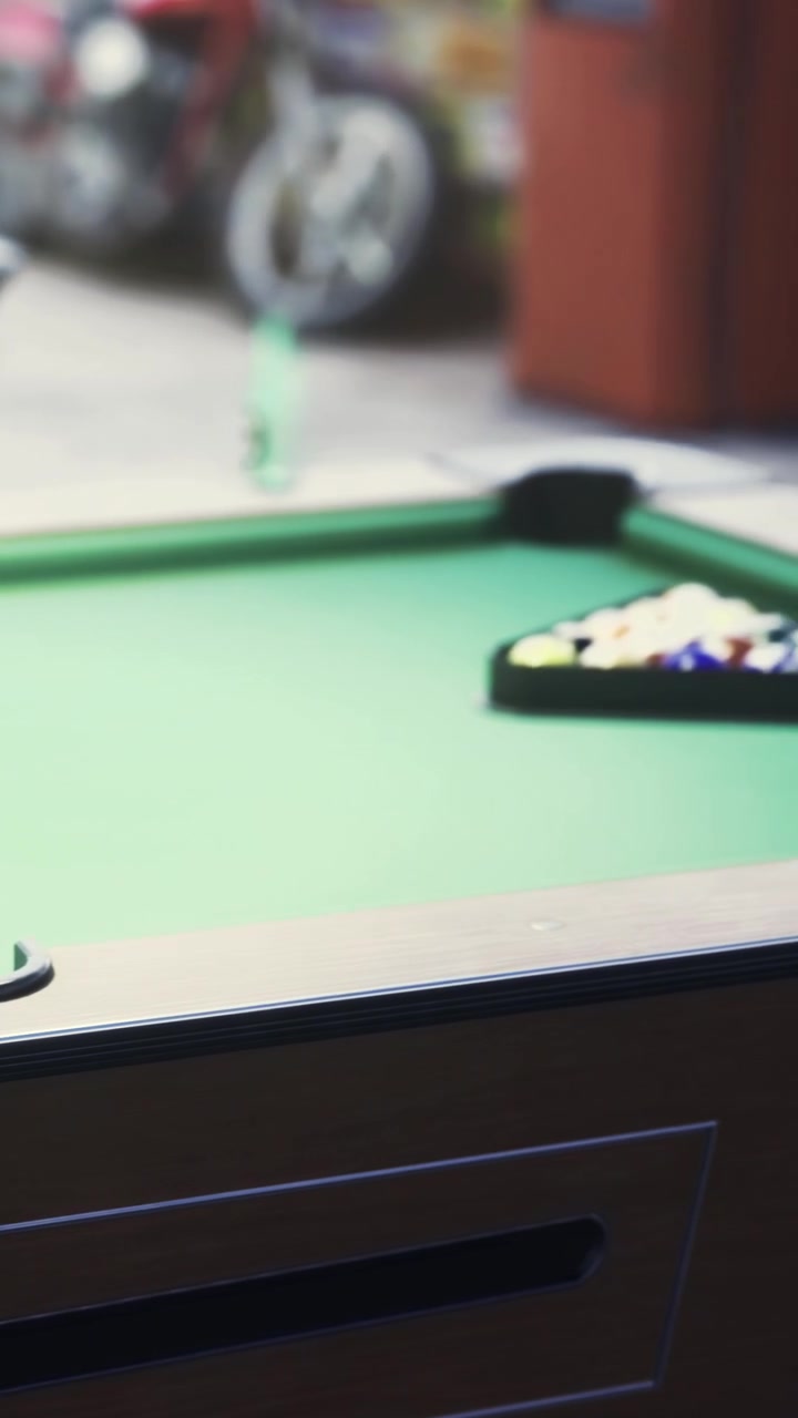 Pool table with green felt and cue stick rest in a game room setting