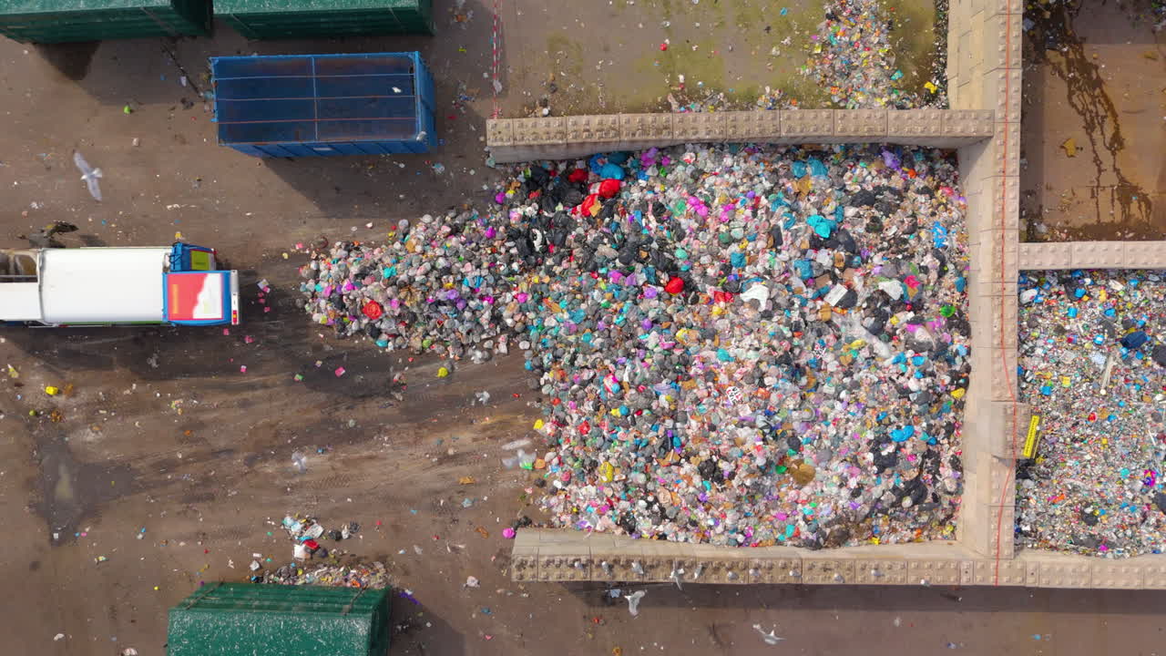 vista aérea de arriba hacia abajo del camión de basura al lado del vertedero de basura con gaviotas en círculo