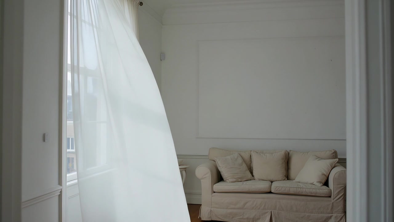 Tenda bianca trasparente che ondeggia e si muove nel soggiorno, con una brezza costante che spinge attraverso il divano beige.