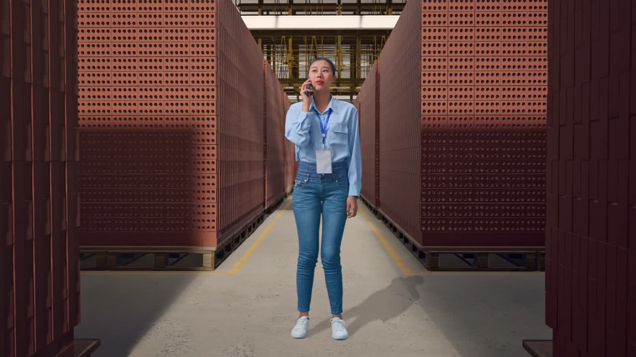 Full Body Of Asian Female With Red Brick Packed in Stacks Are Stored, She Is Speaking With Someone In The Phone