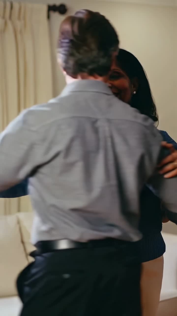 Video verticale: Tenendosi per mano, coppia matura che ondeggia a casa, con maglietta blu e camicia grigia che mostrano gli anelli