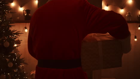 Santa-brings-a-gift-to-children-on-Christmas-night-and-puts-it-near-the-Christmas-tree-in-the-children-house.-the-camera-monitors-the-delivery-of-the-gift-under-the-tree.-High-quality-4k-footage