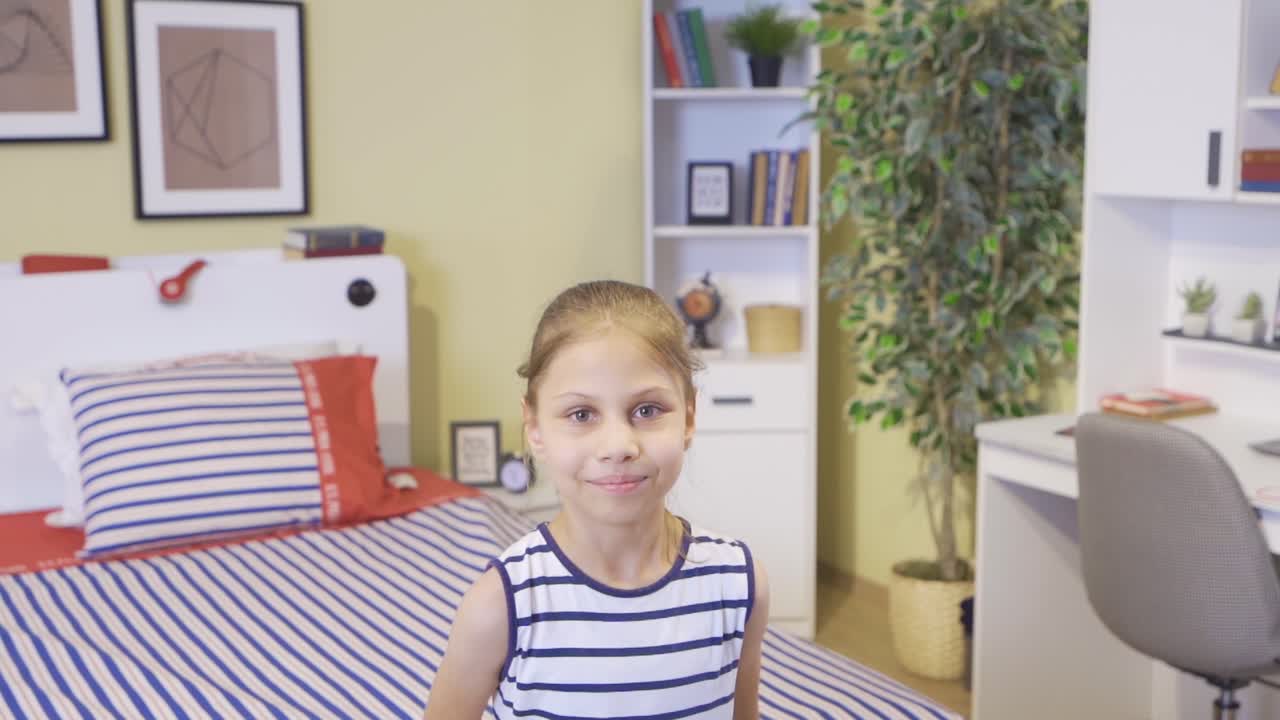 riendo a la cámara, la chica salta en su cama.