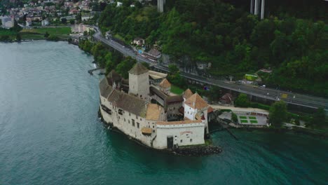 Retrocediendo-Desde-El-ángulo-Del-Dron-Donde-Hay-Muchos-árboles-Detrás-Del-Castillo-De-Chillon