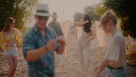 Jóvenes-Amigos-Bailando-En-La-Playa-Durante-La-Puesta-De-Sol