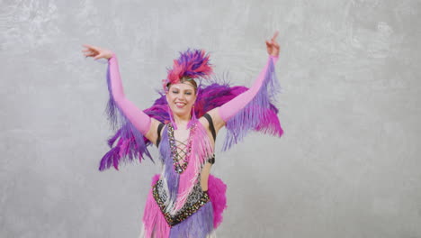 zoom out view of pretty female dancer in a purple and pink feather gown