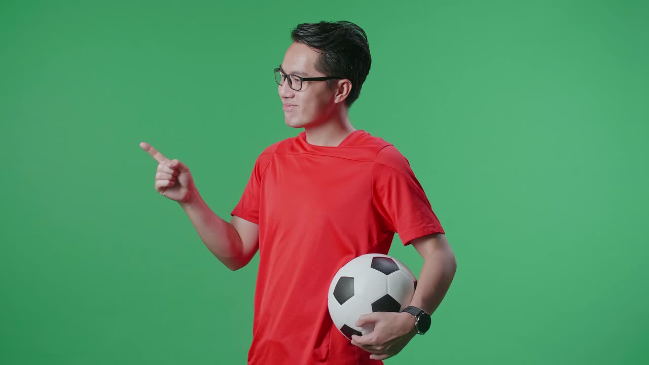 Uomo in maglia da calcio rossa che tiene in mano un pallone da calcio.