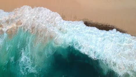 aerial bird's eye view over a bali beach with turquoise sea waves