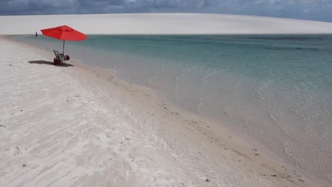 red beach umbrella on the shore of beautiful crystal clear blue lagoon.
