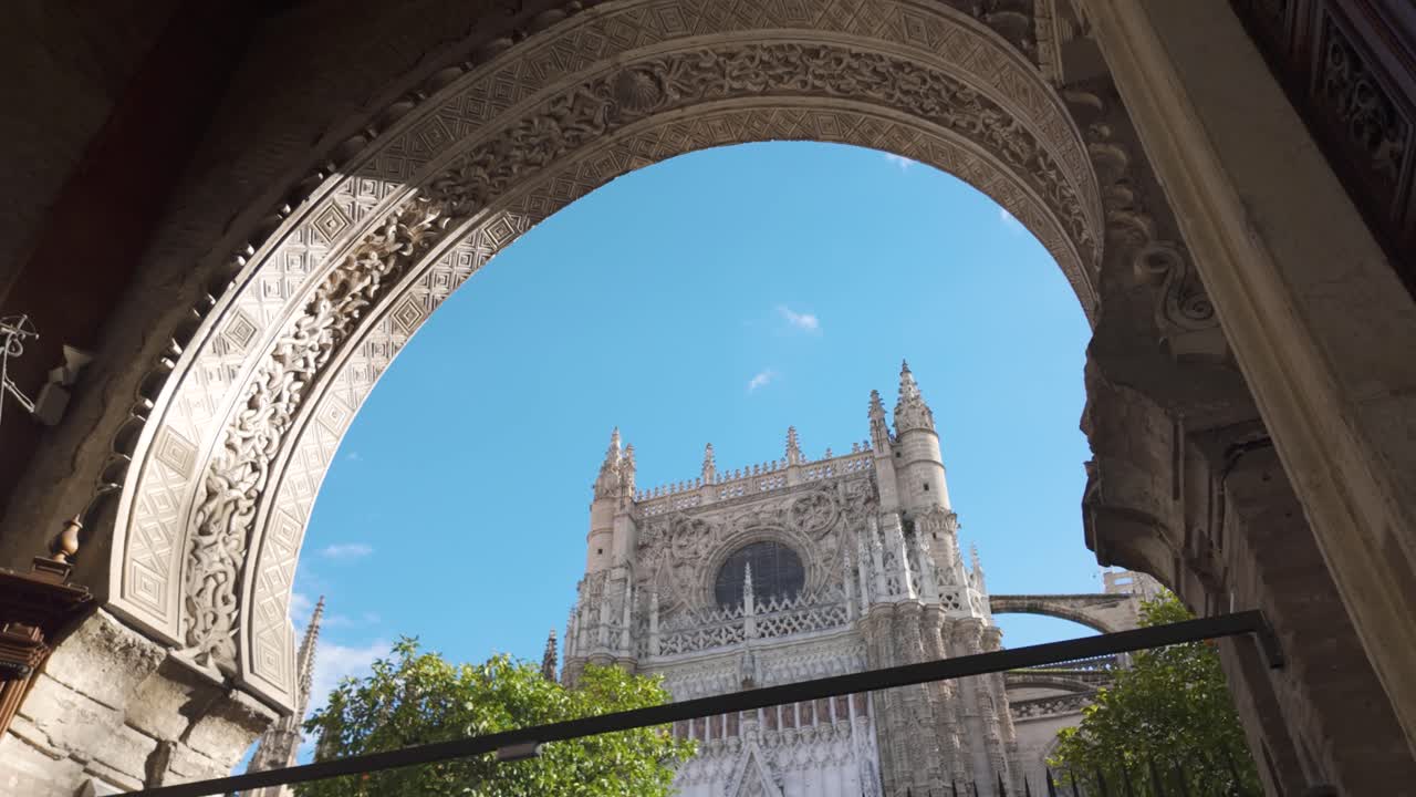 Ornate Gothic facade of Sevilla Cathedral framed by a detailed arch in Seville