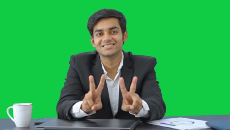 Happy-Indian-businessman-showing-victory-sign-Green-screen