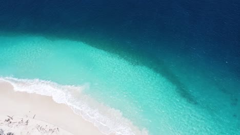 aerial drone rising over jaco island, timor-leste in southeast asia, idyllic white sandy beach, crystal clear turquoise water, and deep blue ocean