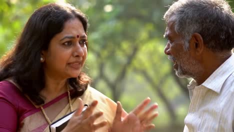 in a serene park, an elderly couple shares a meaningful conversation while surrounded by lush greenery. their expressions reflect deep emotions as they connect over shared memories.