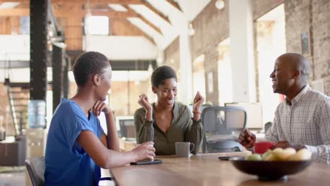 felices colegas afroamericanos hablando y bebiendo café en la oficina creativa, cámara lenta