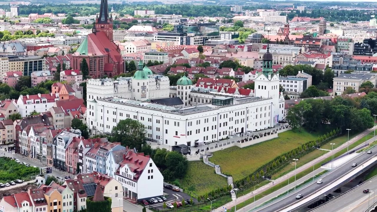 A highangle aerial shot showing the historic white Pomeranian Dukes Castle and the surrounding old town architecture in Szczecin, Poland. Suitable for travel documentaries and urban history.