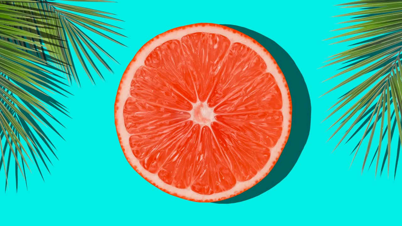 Orange rotate in the sunlight with shadows of palm on a colored blue background. Fruit juices, relaxation, tropics and relaxation concept.