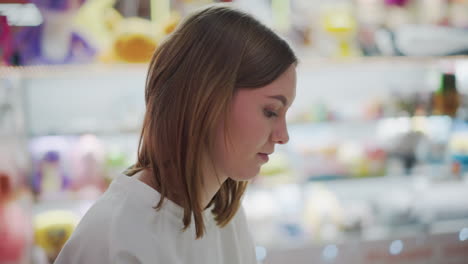 white chic sitting in mall reading yellow book with coffee cup and colorful shopping bags on table, surrounded by soft lighting and vibrant decor, with blurred background of toys