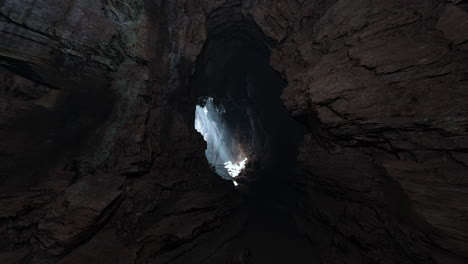 a dark cave entrance with a small light shining through