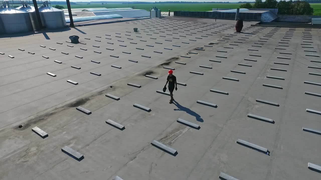 Building the solar farm on flat roof. Flying over the construction site of future alternative power plant on the top of building. Aerial view.