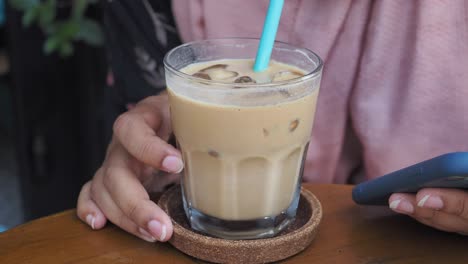 woman sitting at a cafe table enjoying iced coffee