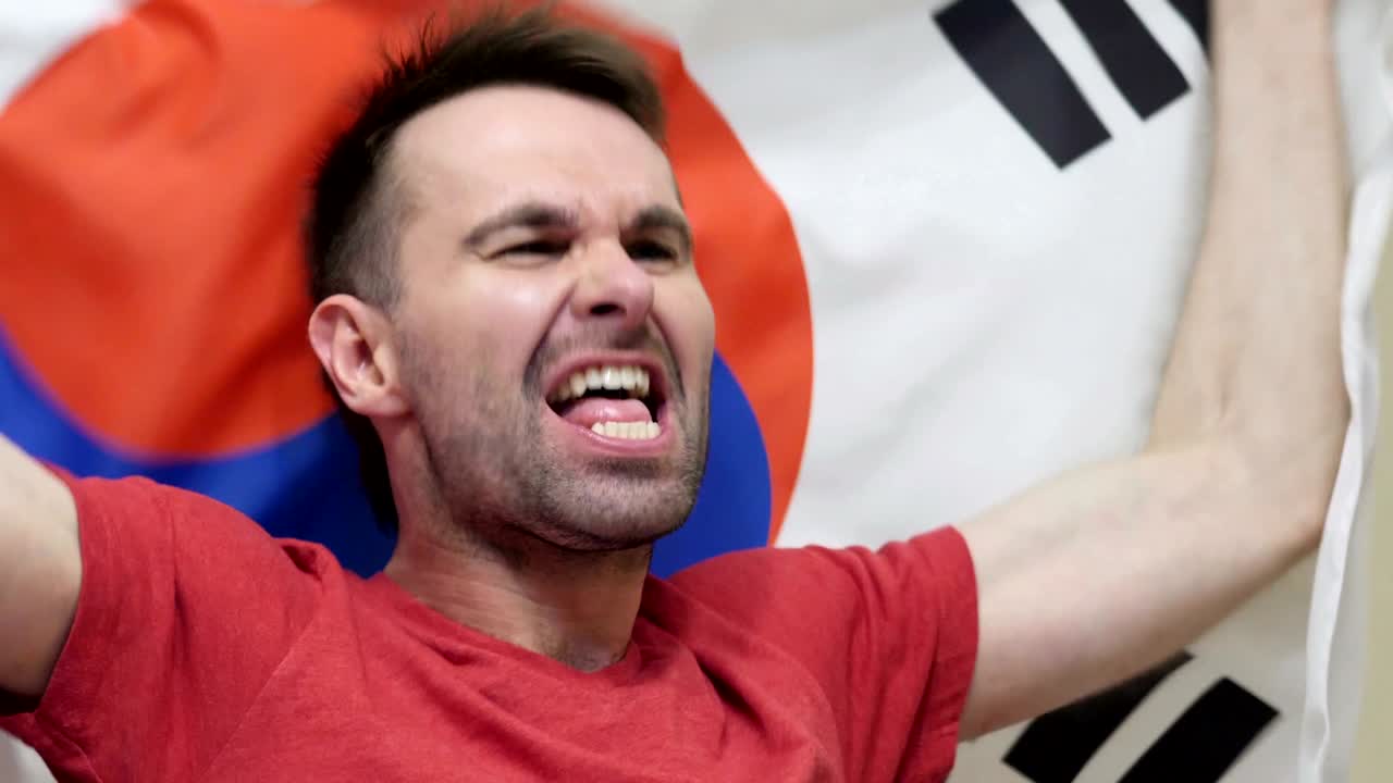 fanático surcoreano celebrando mientras sostiene la bandera de corea del sur en cámara lenta, 4k, de alta calidad