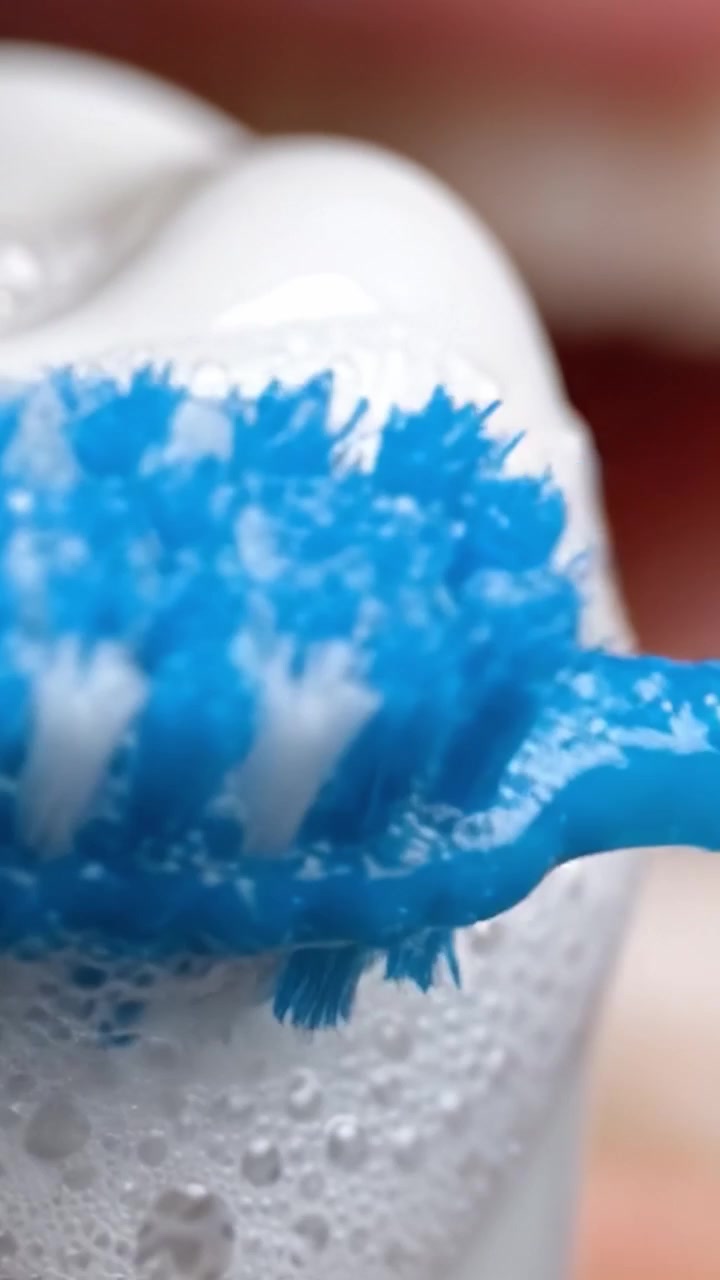 Los pasos esenciales en la higiene bucal: Una vista de cerca de un cepillo de dientes y pasta dental espumosa preparándose para una refrescante experiencia de limpieza.