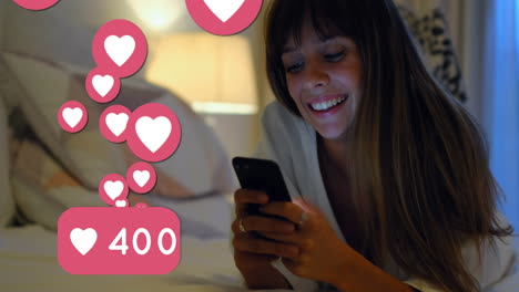 iconos del corazón con números crecientes contra la mujer que usa el teléfono inteligente en la cama
