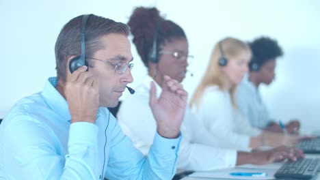 consultor serio del centro de llamadas masculino poniéndose los auriculares