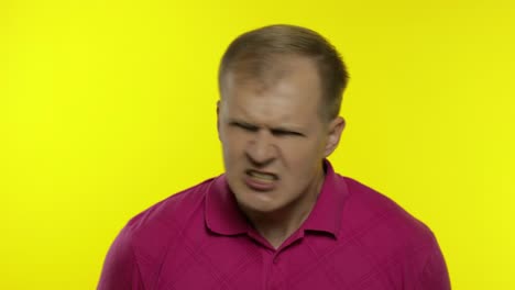 Portrait-of-young-caucasian-man-posing-in-pink-t-shirt.-Handsome-guy-screams-and-gets-angry