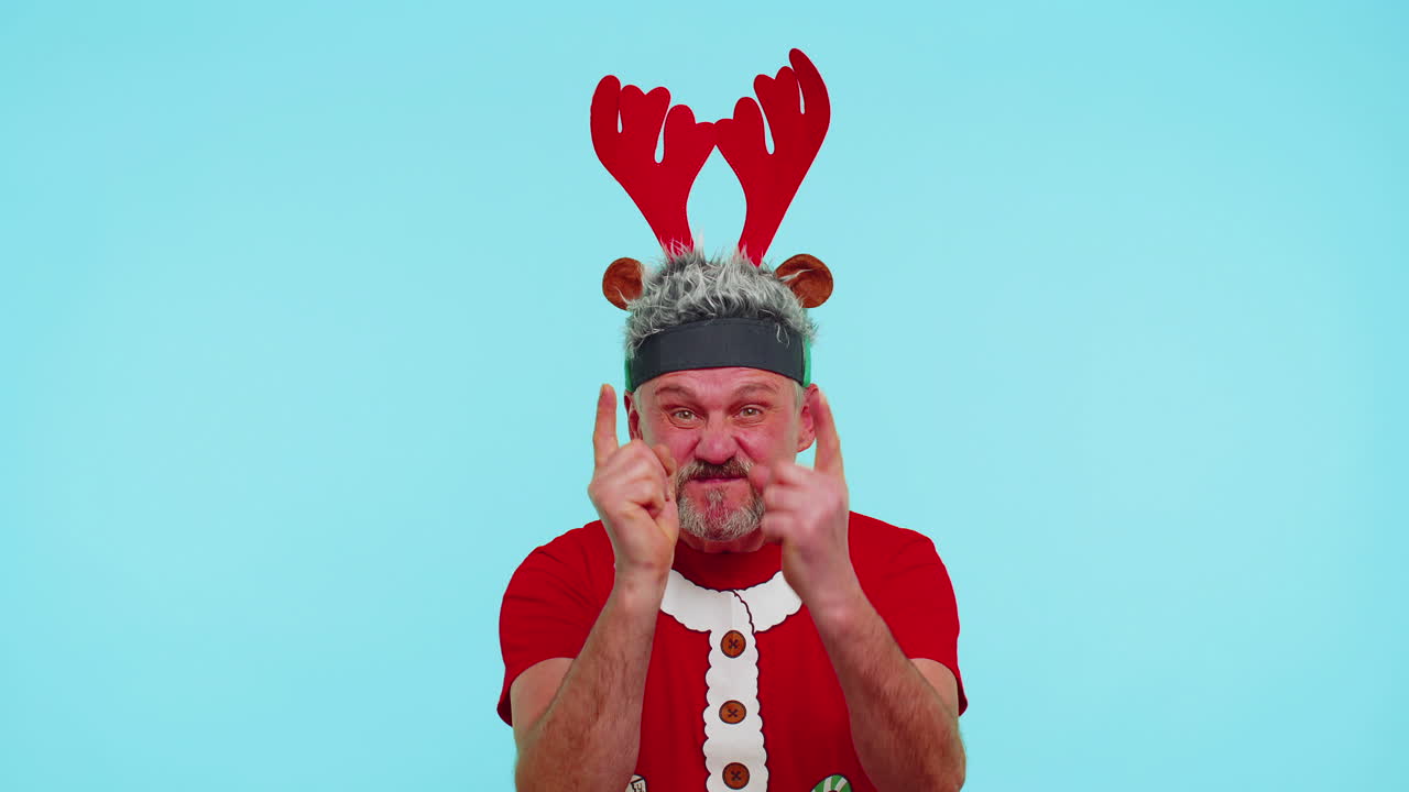 크리스마스 티셔츠를 입은 불만족한 남자가 불만족으로 손을 흔들며 실패에 대한 비난을 비난합니다.