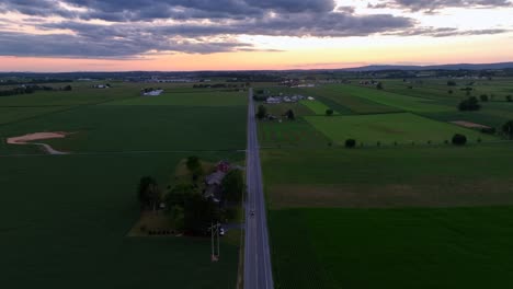 a straight road cuts through farmland in lancaster county at dusk