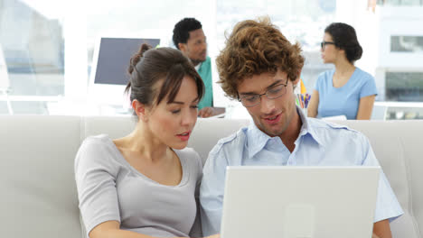 Colleagues-chatting-on-the-couch-with-laptop-