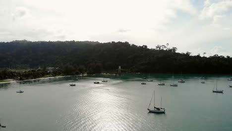 Aerial-View-Of-A-Peaceful-Harbour-With-Lighthouse,-Turquoise-Water-and-Boats