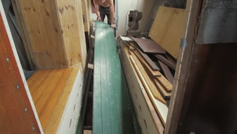 young man lifting floorboard to reveal bilge of wooden boat